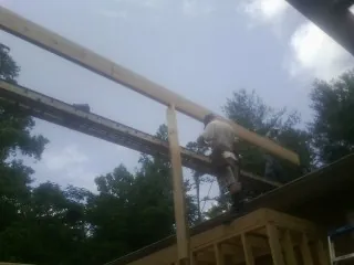 Carpenter setting a ridge beam over a new addition frame — Ice Dam Removal by Roofing Brothers in Mason City