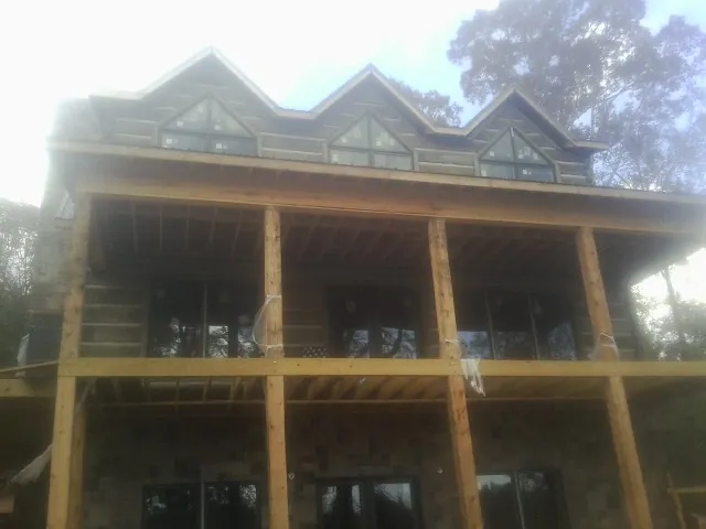 Dormers and porch framing on a large log home under construction — Roof Coating work by our crew in Mason City