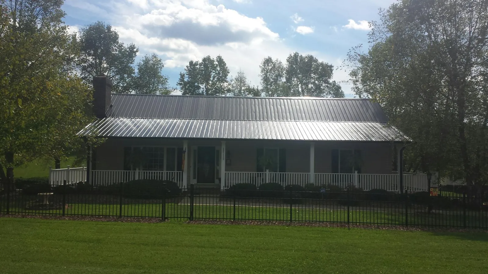 Gray metal roof on a brick ranch with a full width front porch — Gutter Guard Installation work by our crew in Mason City