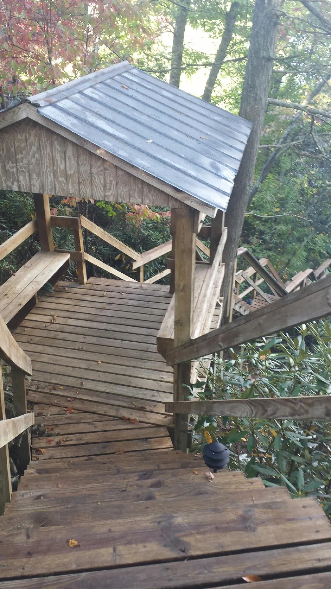Metal roofed shelter over wooden steps on a wooded walkway — Skylight Repair & Installation work by our crew in Mason City