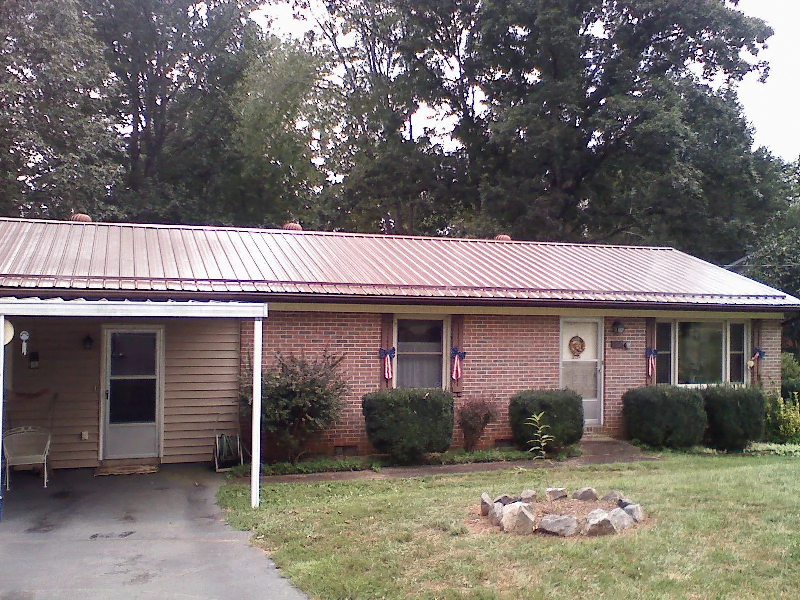 Bronze metal roof and carport on a brick ranch home — Roof Repair work by our crew in Mason City